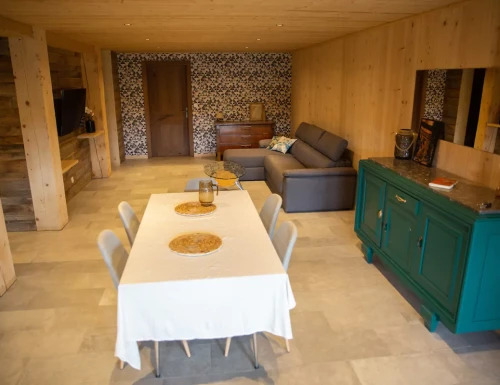 Espace de vie avec table à manger, buffet vert, canapé gris et décoration murale géométrique.Les gîtes du haut bois 2 Le Haut Bois, 25650 Ville-du-Pont, France