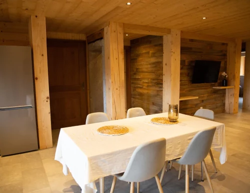 Salle à manger avec table blanche et chaises grises, dans un intérieur en bois naturel.Les gîtes du haut bois 2 Le Haut Bois, 25650 Ville-du-Pont, France