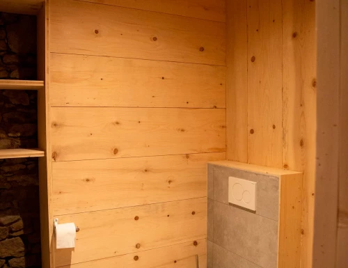 Toilettes décorées avec du bois clair et carrelage gris autour du réservoir encastré.Les gîtes du haut bois 2 Le Haut Bois, 25650 Ville-du-Pont, France