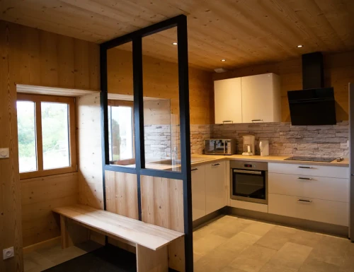 Cuisine moderne avec verrière noire, banc en bois et mobilier blanc, ambiance chaleureuse.Les gîtes du haut bois 2 Le Haut Bois, 25650 Ville-du-Pont, France