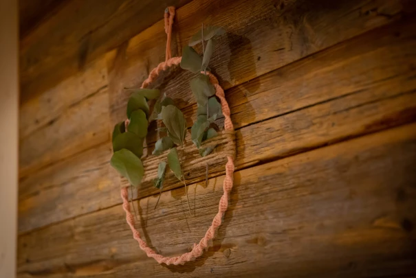 Cercle en corde décoratif avec feuillage accroché sur un mur en bois rustique.Les gîtes du haut bois 2 Le Haut Bois, 25650 Ville-du-Pont, France