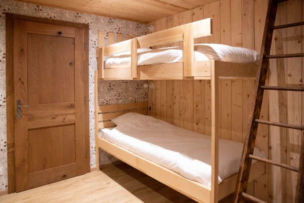 Chambre boisée avec lits superposés en bois clair et mur à motif clair.Les gîtes du haut bois 2 Le Haut Bois, 25650 Ville-du-Pont, France