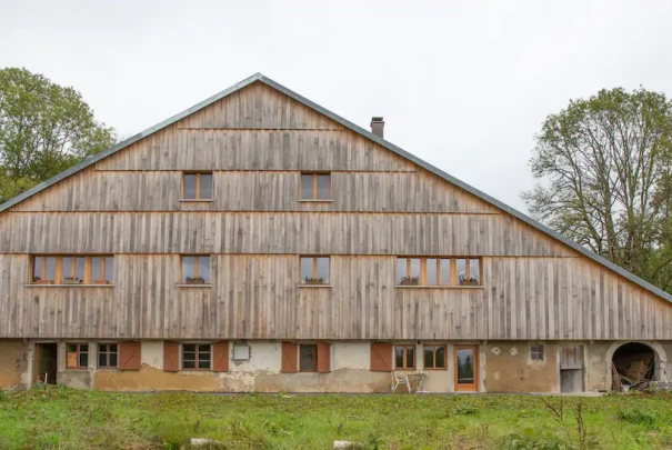 Façade d’une grande bâtisse en bois et pierre, typique des fermes traditionnelles.Les gîtes du haut bois 2 Le Haut Bois, 25650 Ville-du-Pont, France