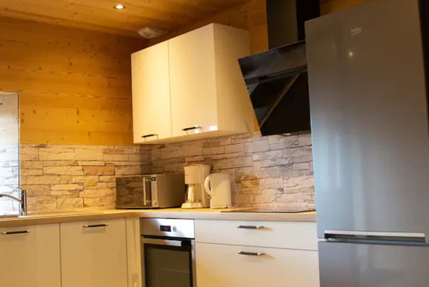 Cuisine moderne avec meubles blancs, électroménagers en inox et murs en bois clair Les gîtes du haut bois 2 Le Haut Bois, 25650 Ville-du-Pont, France