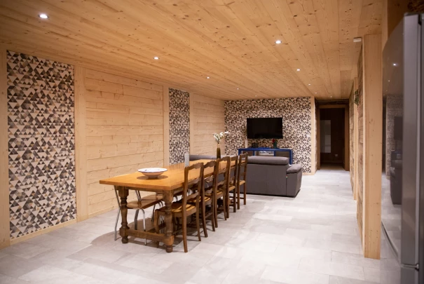 Grande pièce avec plafond en bois, table à manger en bois massif et salon avec canapé et télévision.Les gîtes du haut bois 2 Le Haut Bois, 25650 Ville-du-Pont, France