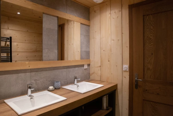 Espace salon avec canapé gris et meuble TV bleu, murs en bois et décoration murale texturée.Les gîtes du haut bois 2 Le Haut Bois, 25650 Ville-du-Pont, France