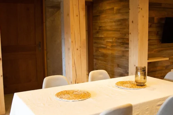 Salle à manger avec table blanche et chaises modernes dans un intérieur chaleureux en bois. Les gîtes du haut bois 2 Le Haut Bois, 25650 Ville-du-Pont, France