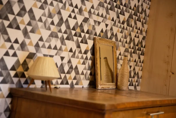 Commode en bois avec miroir et décoration, devant un mur aux motifs géométriques.Les gîtes du haut bois 2 Le Haut Bois, 25650 Ville-du-Pont, France

