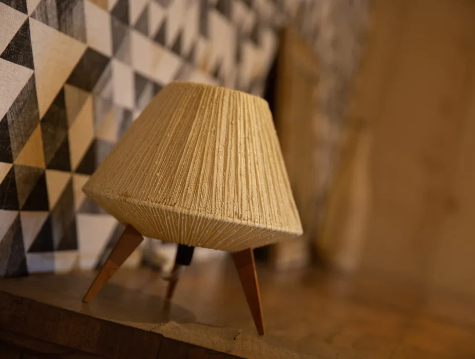 Petite lampe décorative en rotin posée sur un meuble en bois, devant un mur géométrique noir et blanc.Les gîtes du haut bois 2 Le Haut Bois, 25650 Ville-du-Pont, France